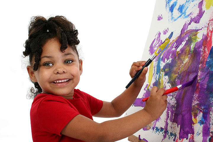 A young preschool-aged girl is working on an easel.