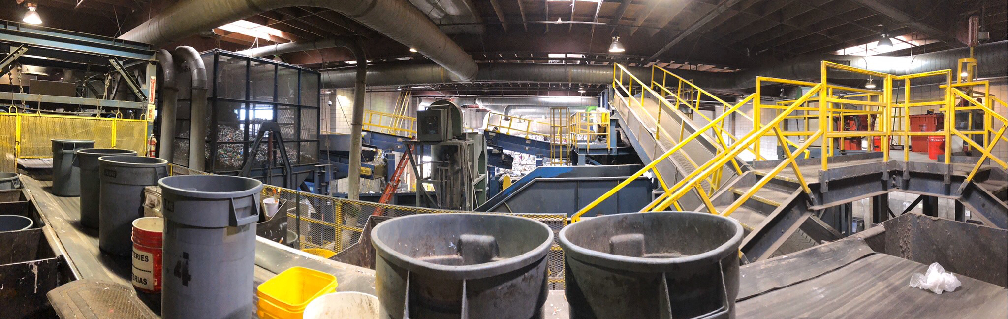 A wide-angle shot of inside the material reclamation facility; bins are on a conveyer belt in the foreground.