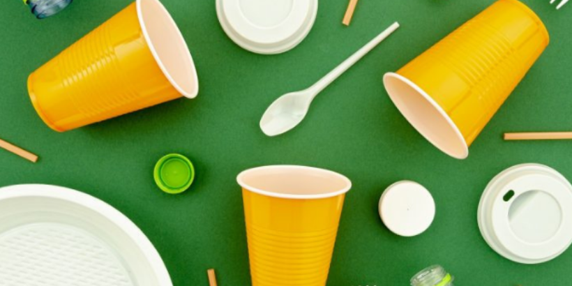 Polystyrene cups, plastic bottle caps, disposable plastic spoons, coffee cup toppers, chop sticks and a plastic plate on a green felt background.
