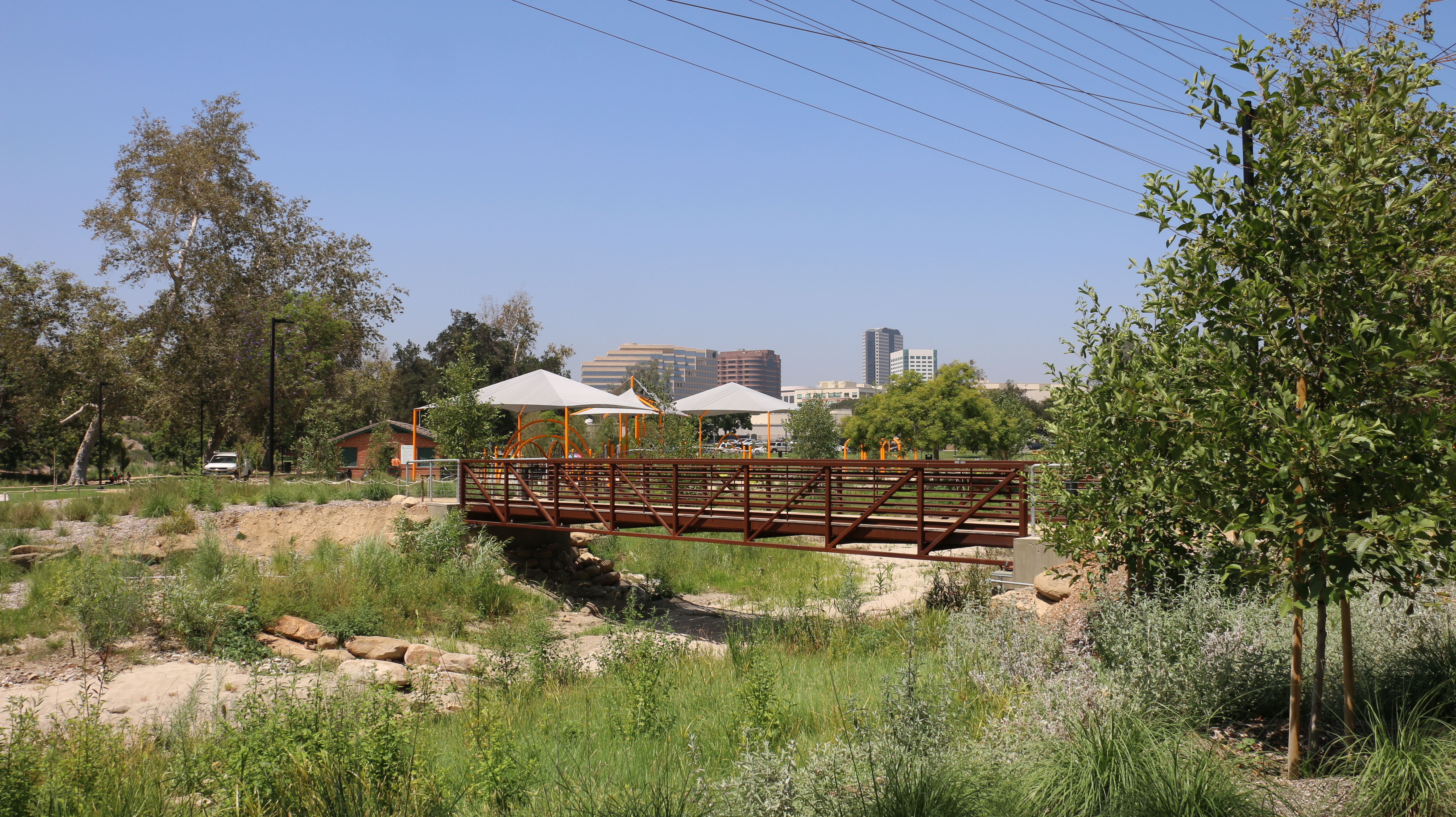 A photo of Johnny Carson Park playground, shade structure, and children playing.