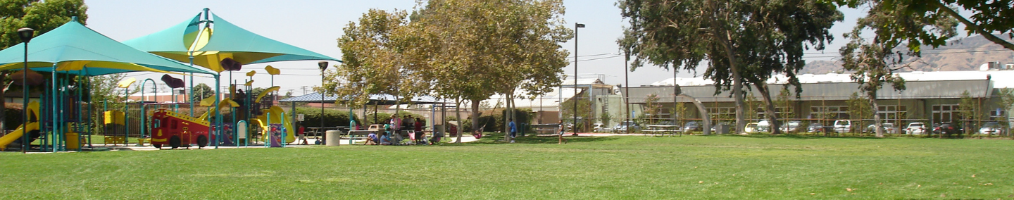A photo of Johnny Carson Park playground, shade structure, and children playing.