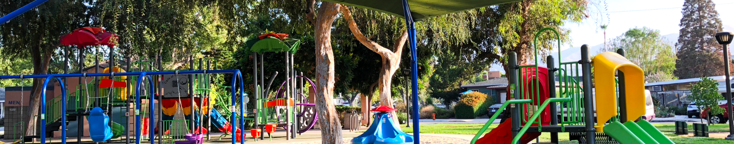 A photo of Johnny Carson Park playground, shade structure, and children playing.
