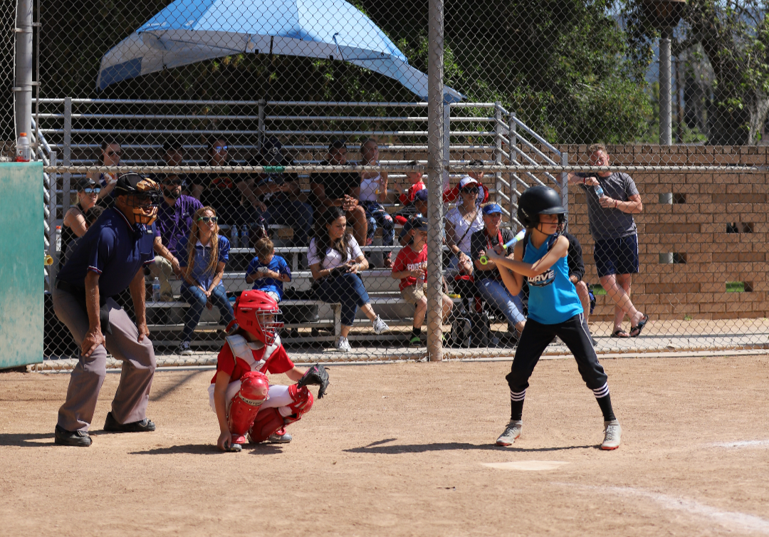 A young female batter is up to plate at Olive Ball Field.