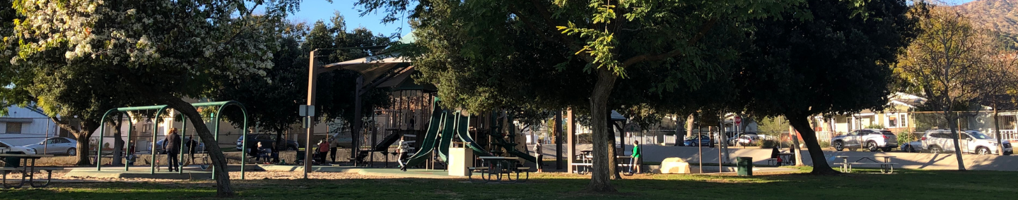 A photo of Johnny Carson Park playground, shade structure, and children playing.