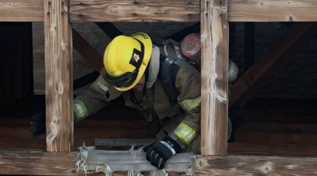 Firefighter crawling through a wooden structure