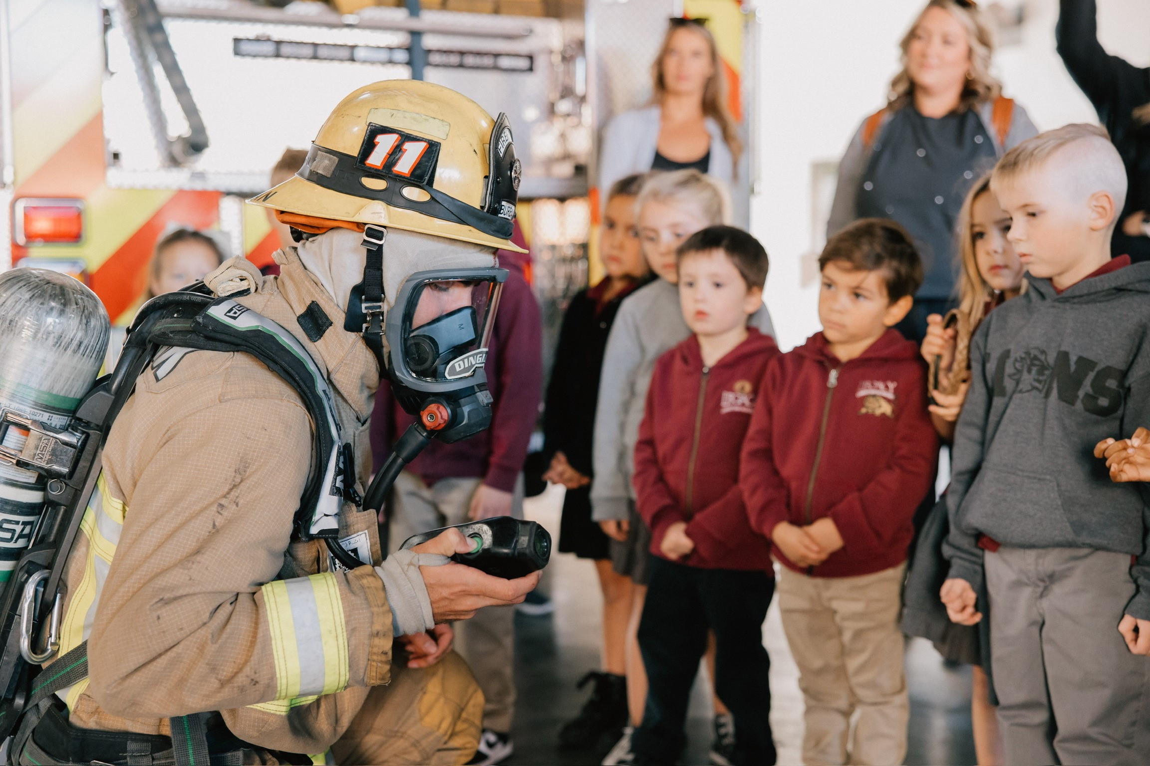 Fireman giving a demonstration to a group of kids and their parents