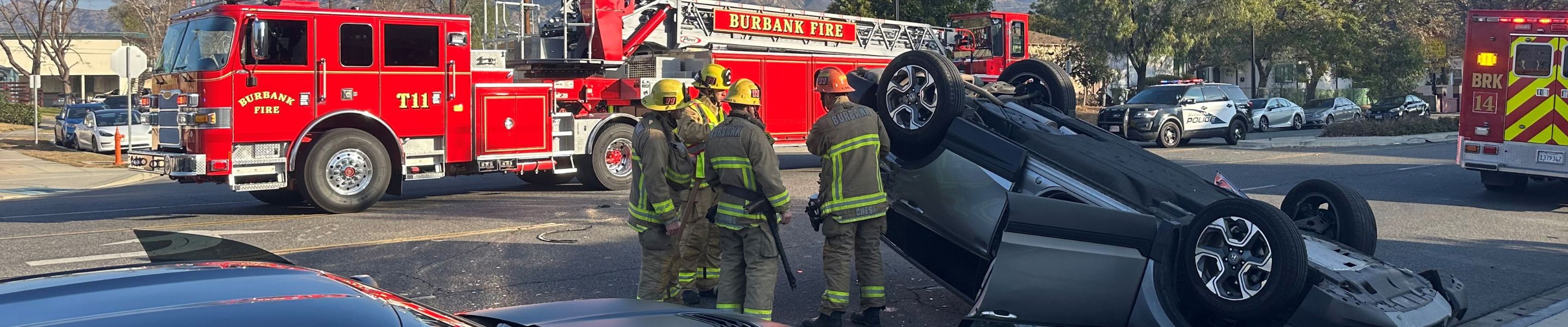 Burbank firefighters respond to an overturned car, with the fire truck in the background