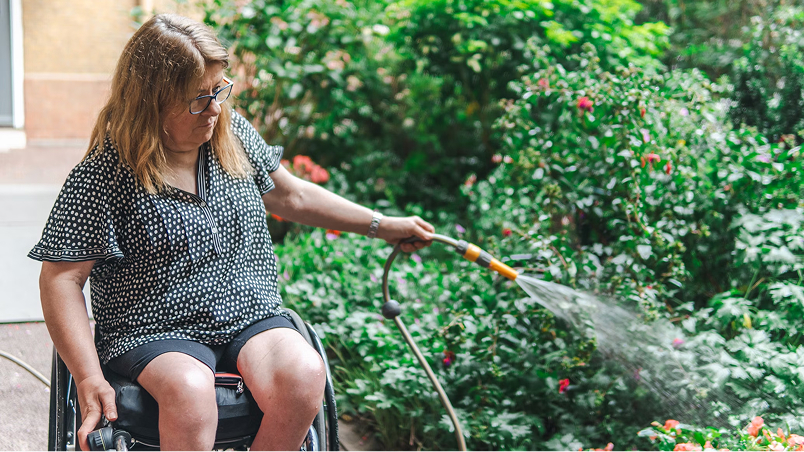 woman in wheelchair watering her garden