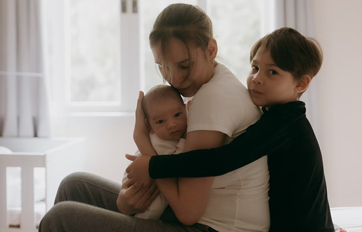 woman hugging young children at home