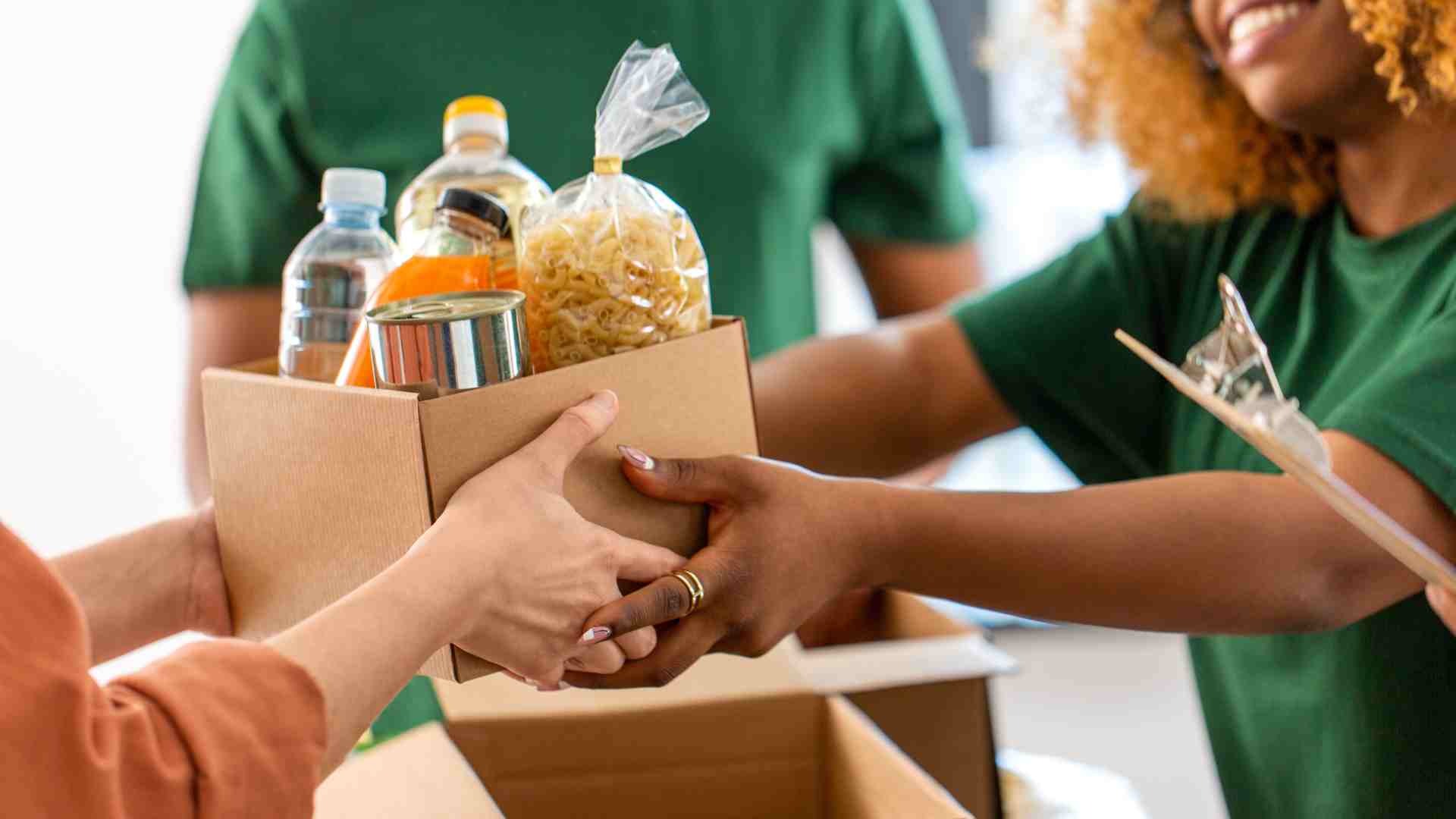 A small cardboard box of food items exchanging hands.